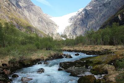 Stream flowing through rocks against sky