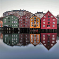 Buildings by river against sky