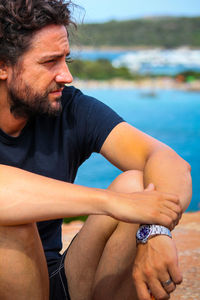 Midsection of man sitting by swimming pool