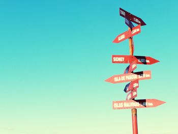 Low angle view of road signs against clear blue sky