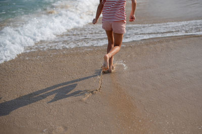 Rear view of woman walking on sand at beach