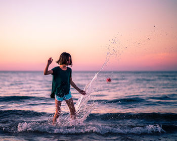 Full length of boy standing on beach against sky during sunset