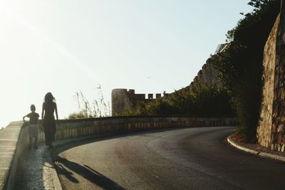 Rear view of people standing on road against clear sky