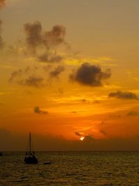 Silhouette of sailboat in sea during sunset