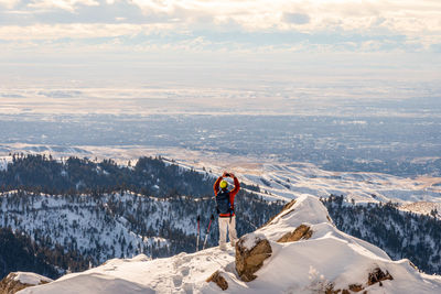 Rear view of man standing on snowcapped mountain against sky