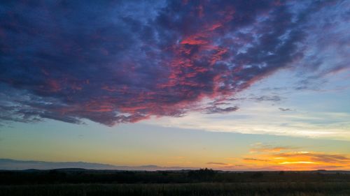 Scenic view of dramatic sky over field during sunset