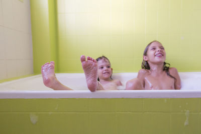 Smiling siblings playing in bathtub