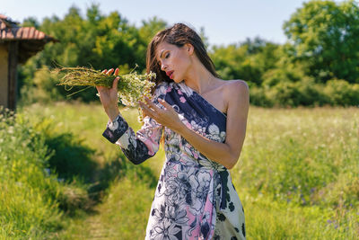 Midsection of woman holding umbrella while standing on field