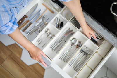 Midsection of woman opening drawer in kitchen