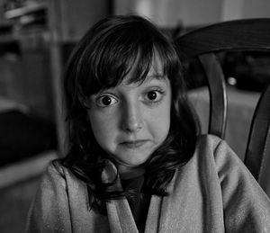 Close-up portrait of girl sitting on chair