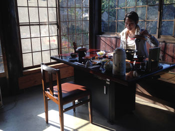 Mid adult woman holding lid by dinning table at home