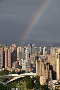 Rainbow over city buildings against sky