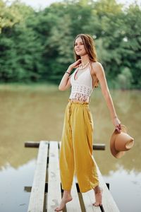 Young woman with arms raised standing against trees