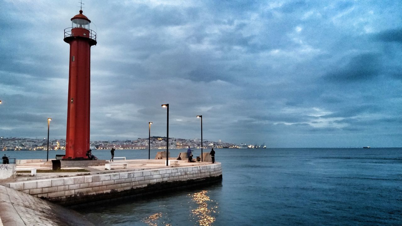 sea, water, sky, built structure, lighthouse, cloud - sky, architecture, horizon over water, pier, waterfront, guidance, cloudy, tranquility, building exterior, nature, scenics, cloud, street light, tranquil scene, incidental people