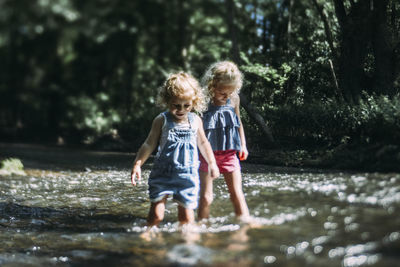 Sisters wading in lake during sunny day