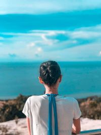 Rear view of woman looking at sea against blue sky