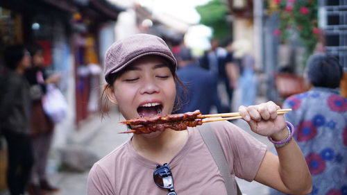 Woman eating food while standing in market