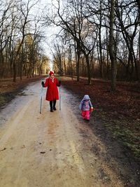 Rear view of father with daughter walking in forest