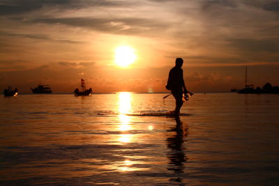 Silhouette man on beach against sky during sunset