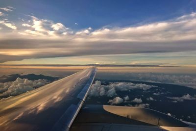 Airplane wing against sky during sunset