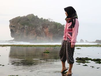 Full length of woman standing on shore against sky