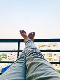 Low section of man resting against clear sky