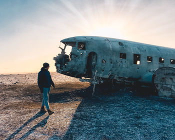 Man standing on airplane against sky during sunset