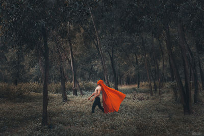 Man standing on field against trees in forest