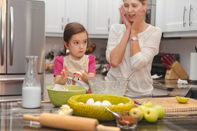 Portrait of mother and daughter standing on table at home