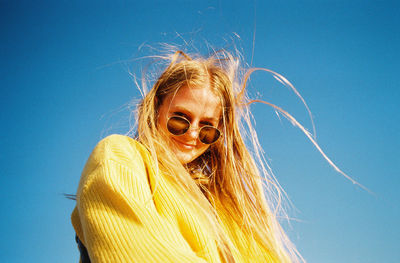 Portrait of smiling woman against blue sky