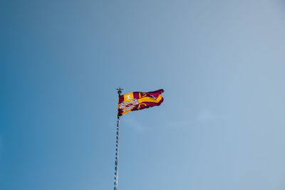 Low angle view of flag against clear blue sky