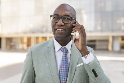 Happy mature businessman talking on mobile phone at financial district