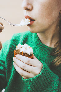 Woman eating icing on cupcake with fork