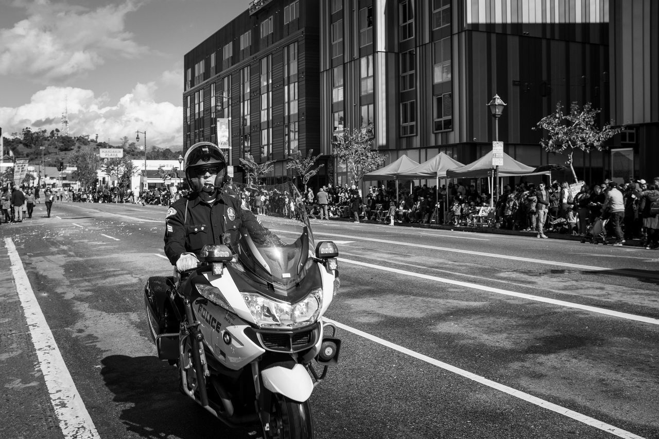 building exterior, city, street, architecture, road, transportation, built structure, real people, motorcycle, men, mode of transportation, day, land vehicle, helmet, people, incidental people, lifestyles, riding, sign, outdoors