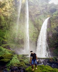 Woman standing on rock against waterfall