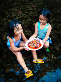 Side view of young woman holding food at beach