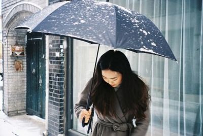 Woman looking through wet window in rain