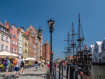 People on street by buildings against clear sky