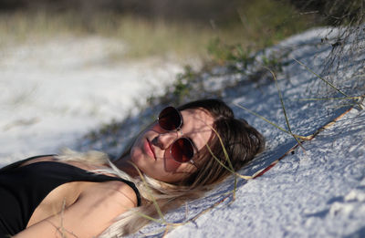 Resting young woman in black bikini and brown sunglasses on beach in eastern australia