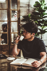 Young man looking away while sitting on table