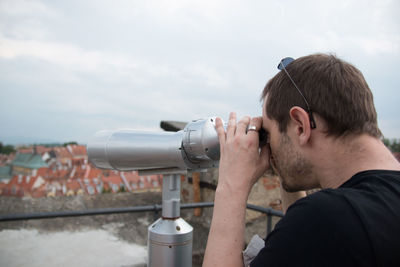 Man looking through binoculars against clear sky