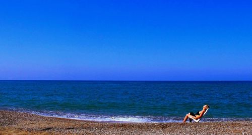 Woman on beach against clear blue sky