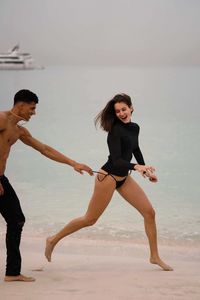 Full length of young couple running chasing at the beach