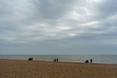 People standing on beach against sky