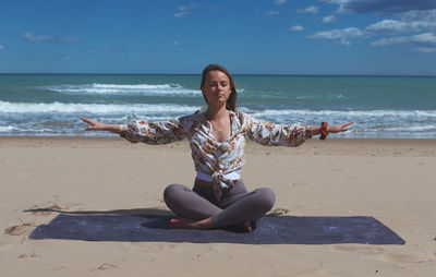 Young blond woman on the beach doing pilates, yoga