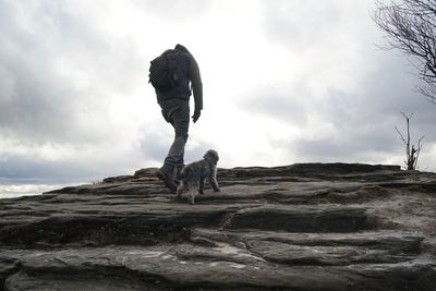 Man on rock by sea against sky