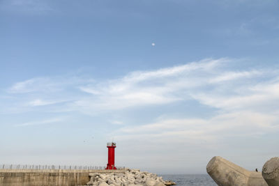 Lighthouse by sea against sky