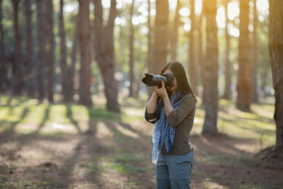 Woman photographing in forest 