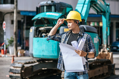 Man working with umbrella standing against built structure