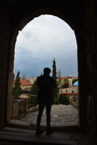 Rear view of silhouette man standing against buildings in city